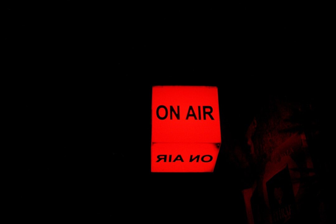 Dark radio broadcast booth with glowing on-air sign